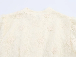 Détail macro du tissu en dentelle abricot avec broderie florale délicate et mesh ajouré