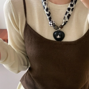 Close-up of leopard fabric strap necklace with checkered beads and heart pendant