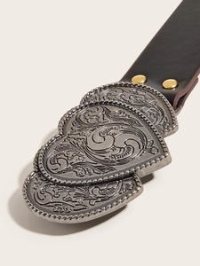 Detail of vintage heart-shaped metal buckle with floral engraving on brown leather belt