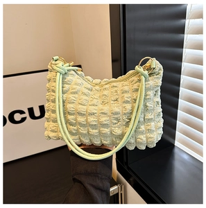 Detail of mint green pleated handbag showing bubble fabric texture and gold ring handle