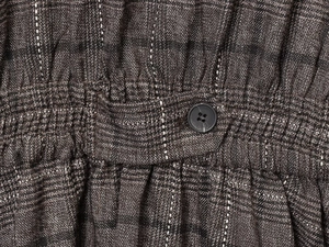 Détail du tissu à carreaux en laine mélangée avec taille élastique et bouton noir sur le pantalon