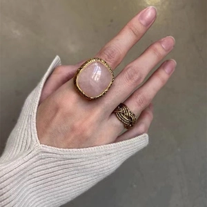 Golden ring set featuring a large pink stone square ring and a braided gold band on hand