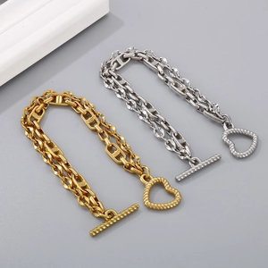 Macro detail of titanium steel chain links and heart-shaped toggle clasp in gold and silver