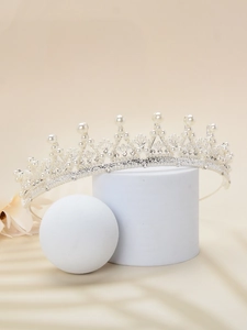 Detail of silver bridal tiara with pearls and rhinestones on elegant white props