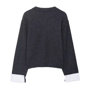 Women's dark grey knitted sweater with white shirt sleeve cuffs shown from the back view