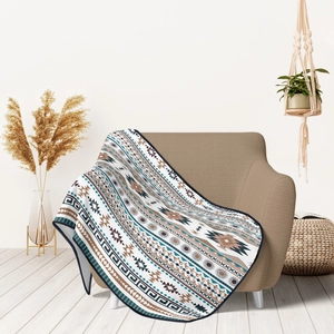 Detail of bohemian geometric blanket with tribal sun patterns on a cozy sofa