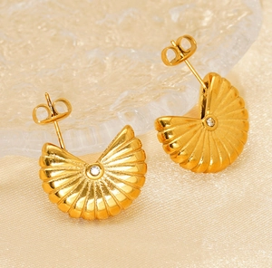 Détail macro de boucles d'oreilles dorées en éventail avec texture coquillage et zircon