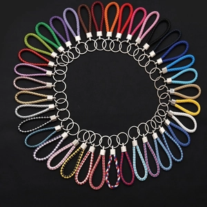 Portachiavi in pelle intrecciata multicolore disposti in cerchio su sfondo nero
