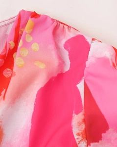 Gros plan sur le tissu à imprimé abstrait rose et orange avec des détails de plis cousus