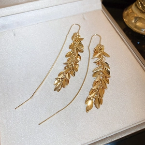 Detailed view of gold plated leaf tassel drop earrings on a grey jewelry display box