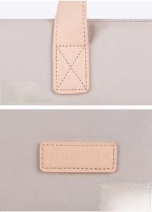 Detail of reinforced stitching on faux leather handle and logo of gray laptop sleeve