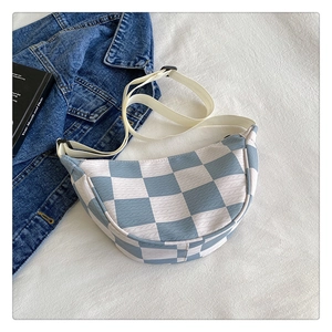 Close-up of blue and white checkerboard crossbody bag with woven texture on fabric
