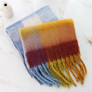 Detailed view of rainbow plaid knit scarf with thick tassels on marble surface