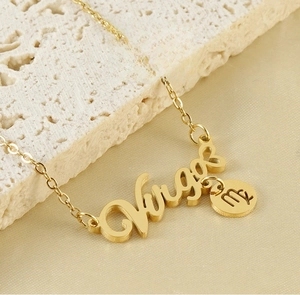 Macro detail of Virgo gold pendant necklace with cursive letters on satin background