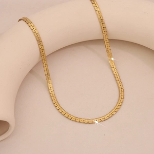Layered gold snake bone chain necklace with elegant woven texture on white display stand