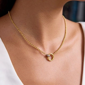Close-up of interlocking gold and silver dual-ring pendant on a delicate chain necklace