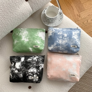 Macro detail of canvas tie-dye makeup bags with metal zipper and brand label