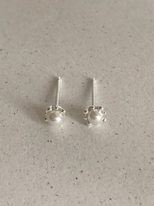 Detail view of 925 sterling silver pearl stud earrings with minimalist claw setting