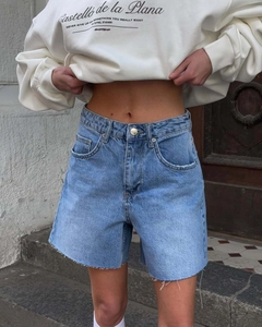 Close-up of light blue high-waisted denim shorts with frayed hems and raw edges