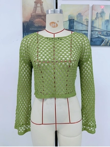 Detail of green crochet knit crop top featuring wide mesh hollow-out design and bell sleeves