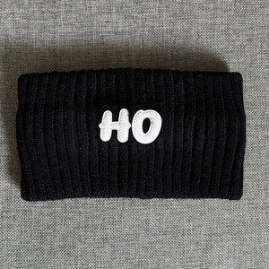Close-up of thick black ribbed knit headband with white HO embroidered patch