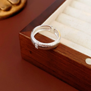 Dettaglio dell'anello d'argento con trama spazzolata e tre pietre di zirconi