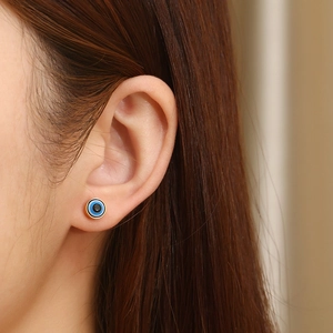 Close-up of shell evil eye stud earrings with gold plating worn on a female model