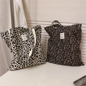 Detail of leopard print canvas tote bags in cream and brown with woven handles