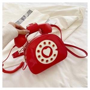 Detail of red patent leather handbag featuring a vintage telephone dial and heart design