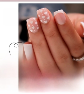 Detail of white French tip press-on nails with small pink heart patterns style #JP2459