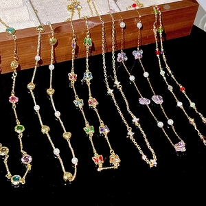 Close-up of golden necklaces with colorful enamel butterflies and faceted gemstones