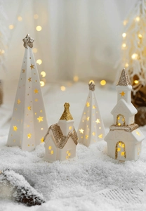 Luminous white ceramic Christmas trees and houses with gold glitter on snowy base
