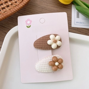 Detail of floral plush fabric hair clips for kids on a pink display card with tulips