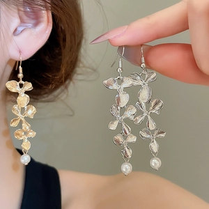 Close-up of silver metal flower drop earrings with white pearl and brushed texture