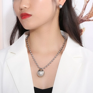 Detailed view of model wearing a hollow ball necklace and matching stud earrings set