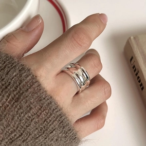 Detail of a chunky multi-layer sterling silver wave ring on finger with soft knit cuff