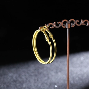 Detailed view of large gold hoop earrings on a vintage stand over a starry black background