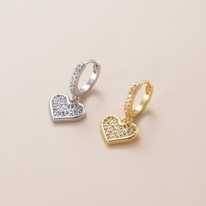 Macro shot of gold and silver heart earrings with sparkling cubic zirconia inlay