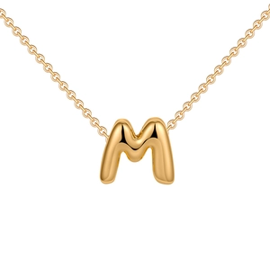 Macro view of polished gold 3D bubble letter M pendant on a delicate chain