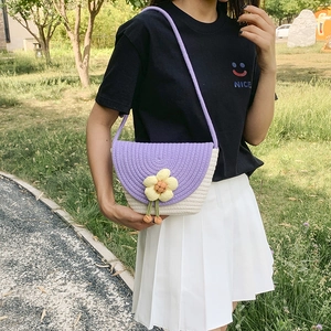 Detail of hand-woven bucket bag with yellow flower charm and purple straw texture