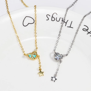 Detail view of heart and planet tassel pendants in gold and silver with inlaid gemstones