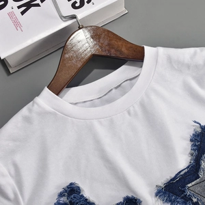 Detail of white cotton T-shirt featuring a blue denim star patch with frayed edges