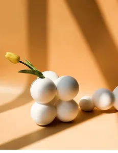 Minimalist white ceramic bubble vase with a yellow tulip in a warm sunlit interior setting