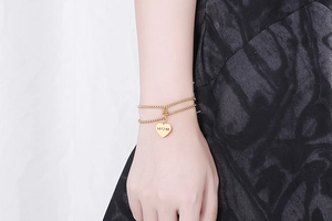 Close-up of a double-layer gold pearl bracelet with a heart-shaped MOM engraved charm