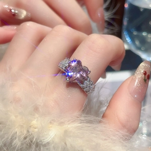 Macro detail of a sparkling pink heart zircon ring on finger with silver cubic zirconia band