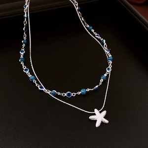 Gros plan du collier pendentif étoile de mer et perles opales bleues sur cuir noir