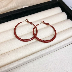 Detailed view of Ancora red twisted hoop earrings on white velvet jewelry display box