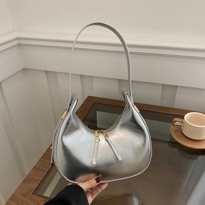 Detailed view of silver metallic crescent underarm bag with stylish double zipper hardware