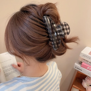 Detail of checkered acrylic hair claw clip worn on head for stylish hairstyling