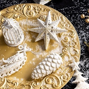 Elegant white star and pinecone Christmas ornaments in a golden tray with silver strings